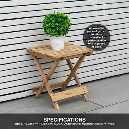 Wooden folding table with a plant on it against a white wooden fence.